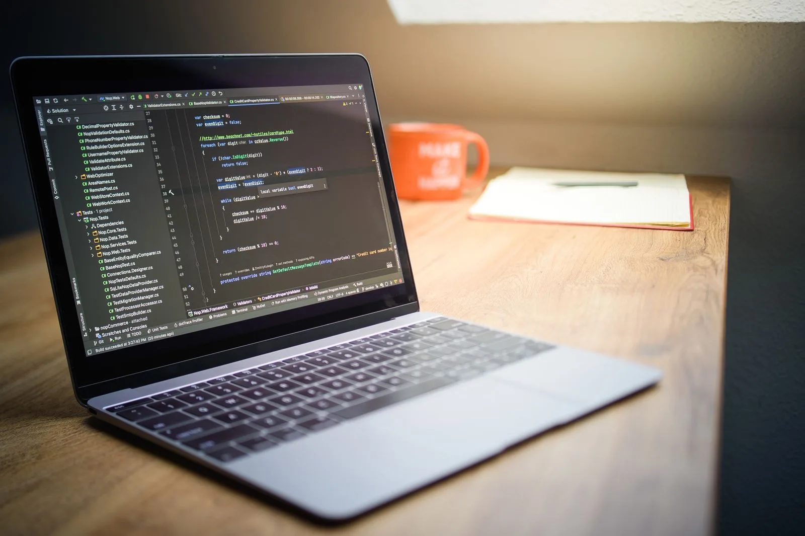 Developer's laptop showing code on a wooden desk, representing a bespoke custom website rebuild