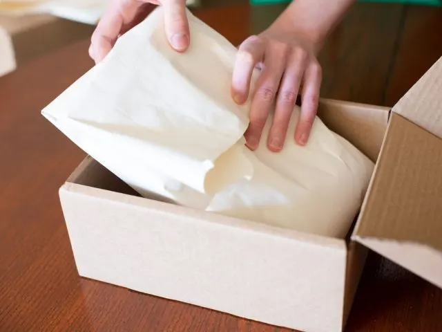 Hands packing a boutique retail order into a box
